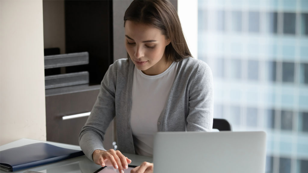 Coordinatrice formation vérifiant les détails de session sur ordinateur portable au bureau